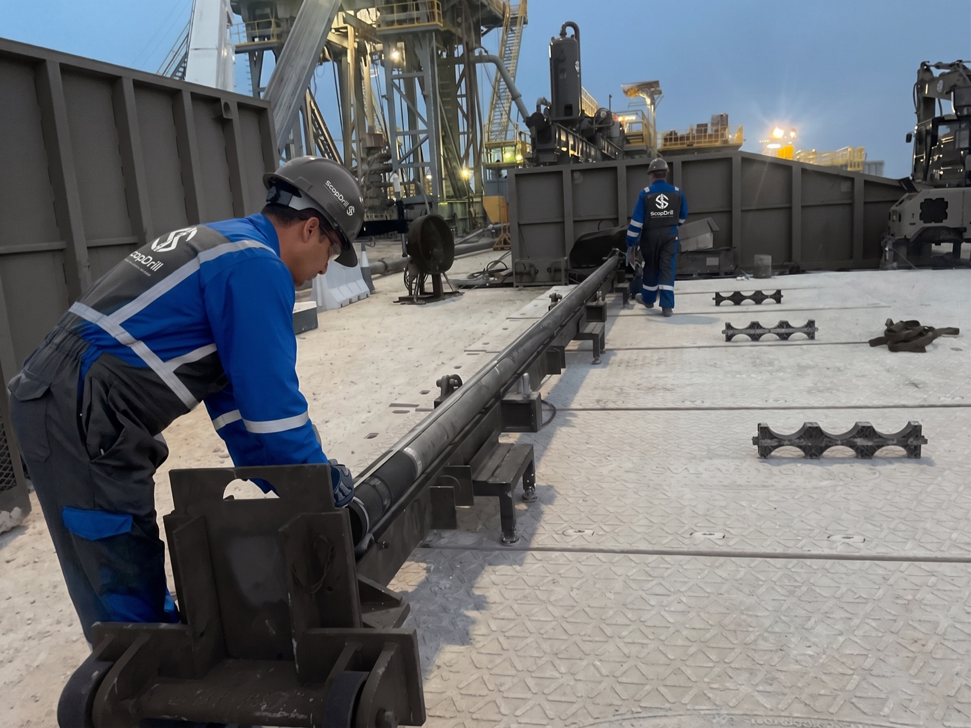 ScopDrill™ technicians handling core barrel assembly on rig floor at dusk